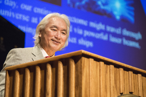 Close view of Michio Kaku behind the lectern with a slide presentation