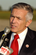 General Wesley K. Clark talking into a microphone at the airport